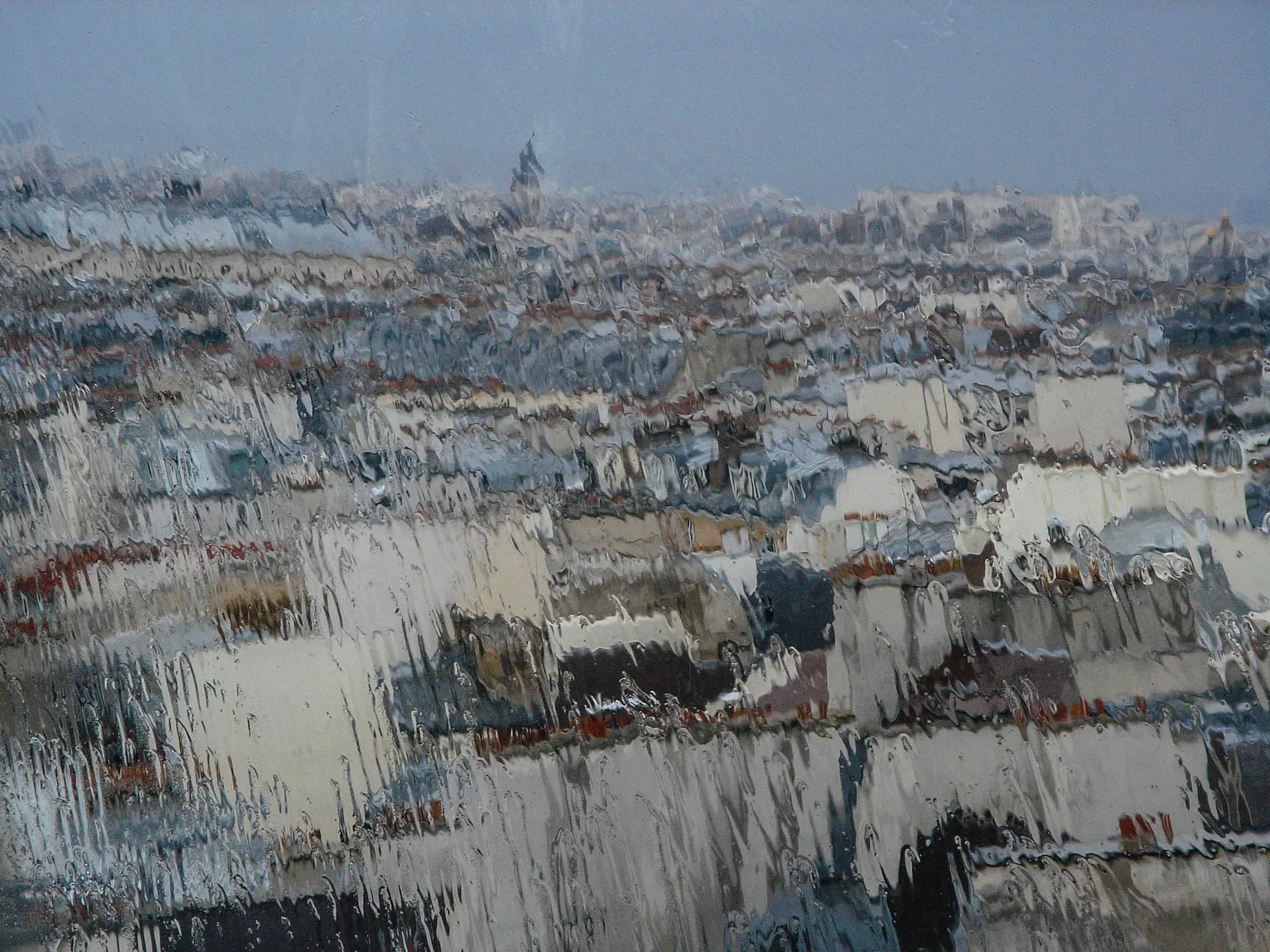 A cityscape of Paris as seen through a rainy window, giving the effect that the image is a semi-abstract oil painting