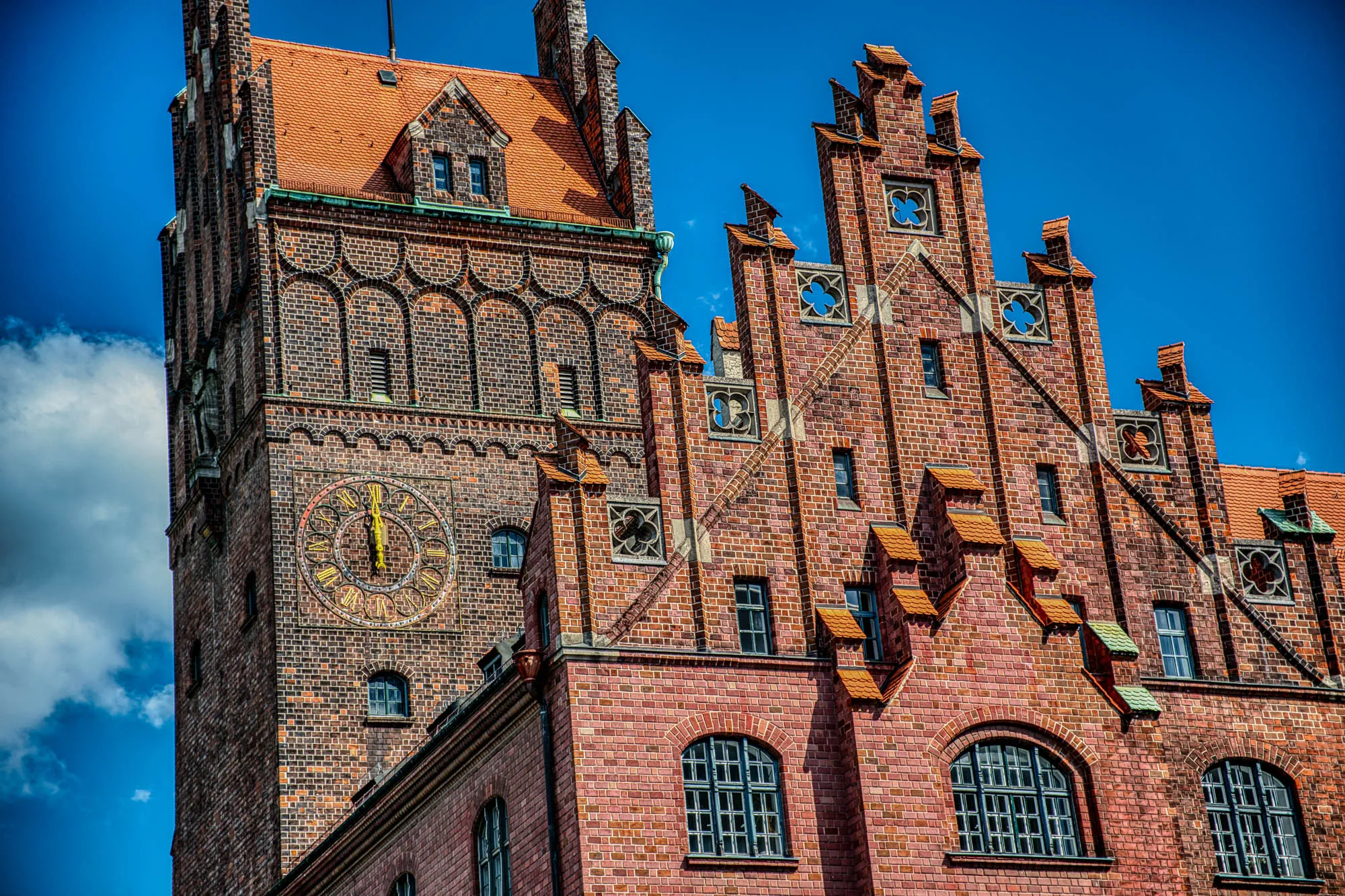 A closeup of the ornate roof and clock tower of the brick higher regional court of Munich